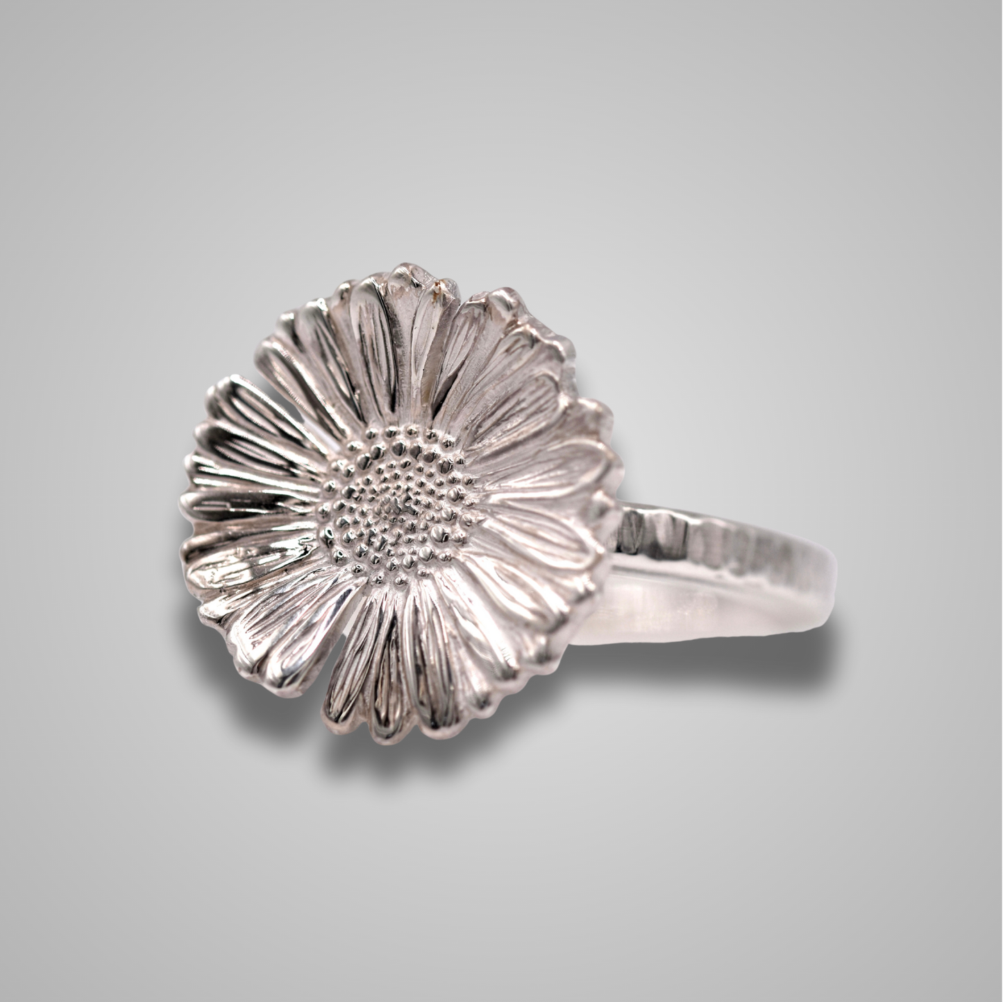 An intricately detailed shiny silver Daisy sits atop a silver band to make a statement ring.